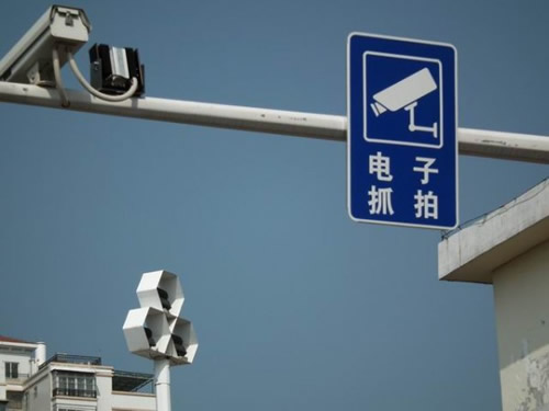 电子警察摄像头旁竖起一块写着"电子抓拍"的警示牌,提醒司机注腋鞲